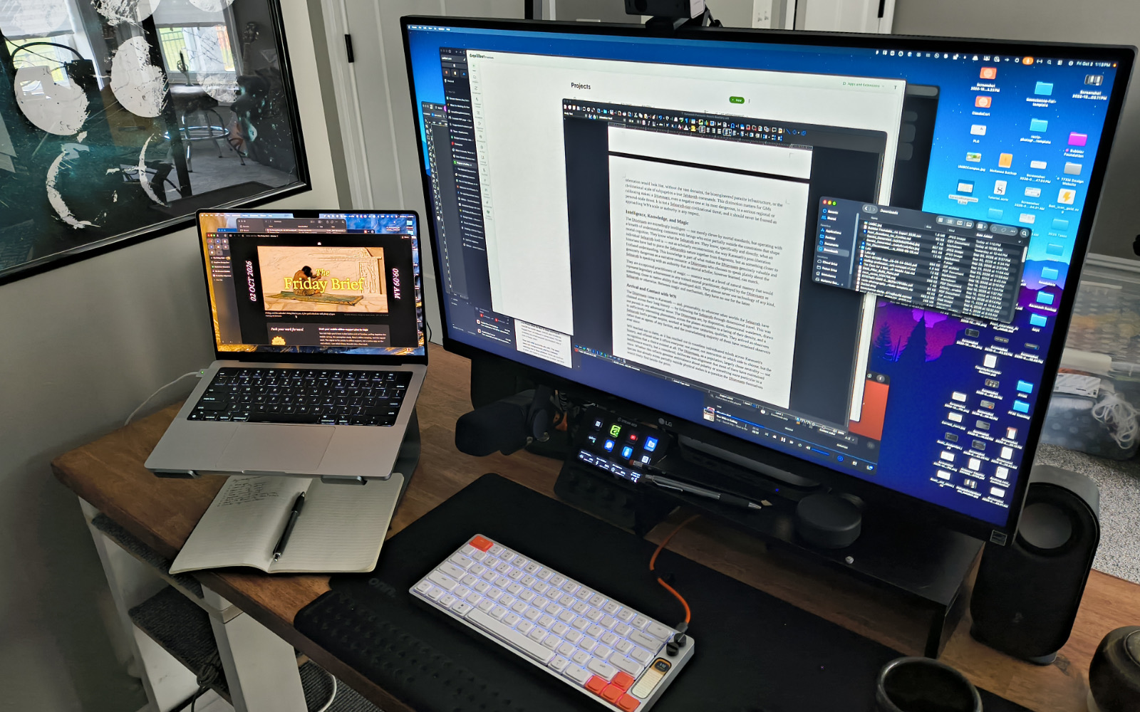Tim’s desk with a large monitor, a laptop on a stand, a notebook, and a compact keyboard.